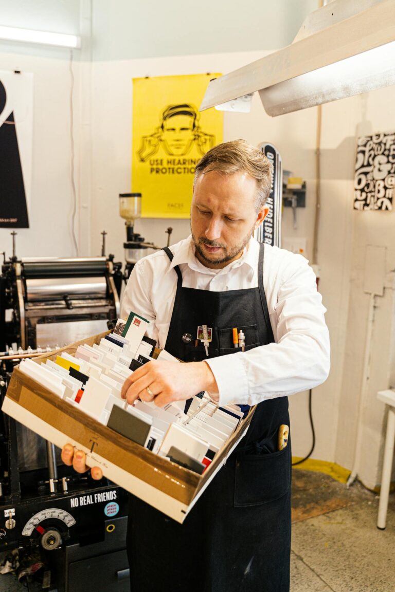 A Man in White Long Sleeves Wearing Black Apron Fixing  Cards on the Box